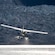 A floatplane approaches the water in front of a huge glacier